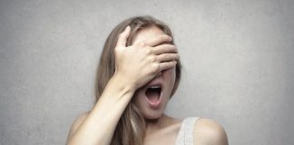 woman in gray tank top covering her face with her hand